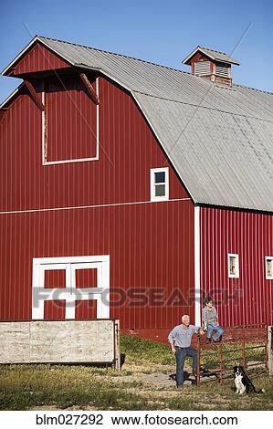 Stock Image - Caucasian ranchers and dog by barn. Fotosearch