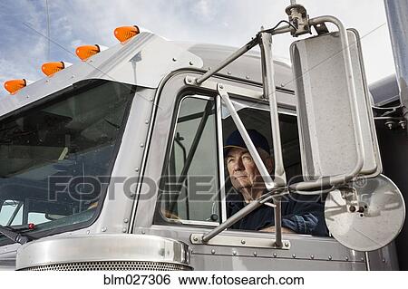 Stock Photograph - Caucasian trucker sitting in semi-truck. Fotosearch
