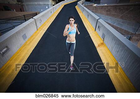 Stock Photography - Caucasian woman running on city street. Fotosearch