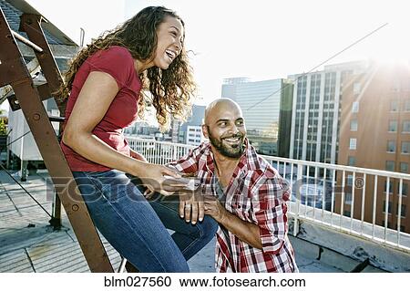 Couple relaxing on urban rooftop View Large Photo Image Stock Image - Couple relaxing on urban rooftop. Fotosearch