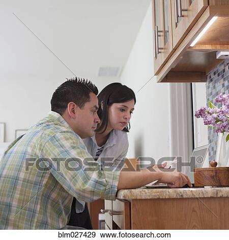 Couple using laptop in kitchen View Large Photo Image Stock Photo - Couple using laptop in kitchen. Fotosearch