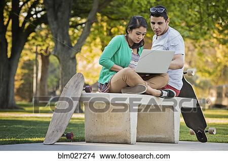 Picture - Couple using laptop together in park. Fotosearch