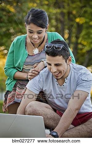 Couple using laptop together in park View Large Photo Image Stock Photo - Couple using laptop together in park. Fotosearch