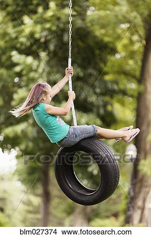 Picture - Girl playing on tire swing. Fotosearch