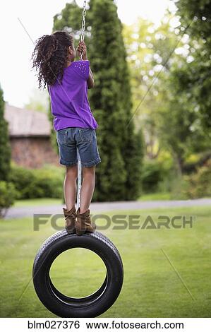 Girl playing on tire swing View Large Photo Image Stock Photograph - Girl playing on tire swing. Fotosearch