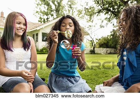 Girls blowing bubbles in backyard View Large Photo Image Stock Photography - Girls blowing bubbles in backyard. Fotosearch