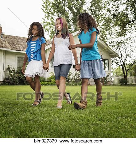 Stock Photo - Girls holding hands in backyard. Fotosearch