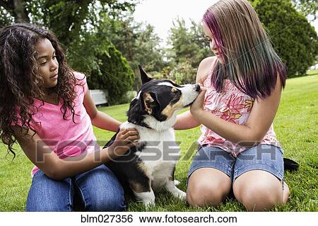 Girls petting dog in backyard View Large Photo Image Stock Photograph - Girls petting dog in backyard. Fotosearch