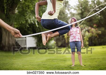 Girls playing jump rope in backyard View Large Photo Image Stock Image - Girls playing jump rope in backyard. Fotosearch