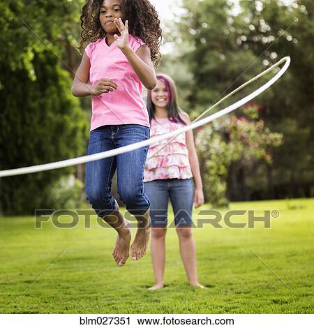 Girls playing jump rope in backyard View Large Photo Image Stock Image - Girls playing jump rope in backyard. Fotosearch