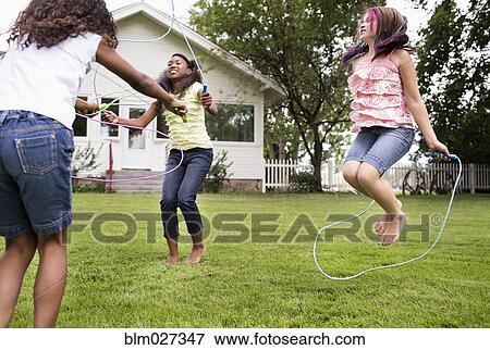 Girls playing jump rope in backyard View Large Photo Image Stock Photo - Girls playing jump rope in backyard. Fotosearch