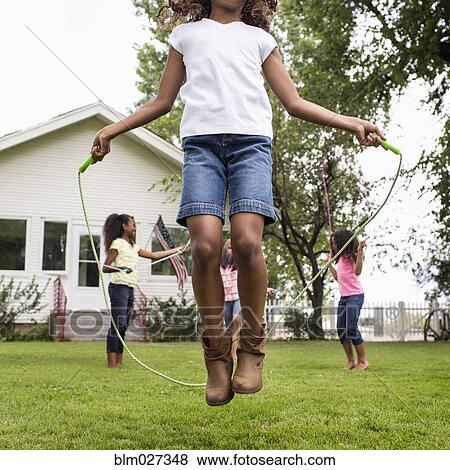 Girls playing jump rope in backyard View Large Photo Image Stock Photo - Girls playing jump rope in backyard. Fotosearch