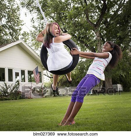Girls playing on tire swing View Large Photo Image Stock Photo - Girls playing on tire swing. Fotosearch