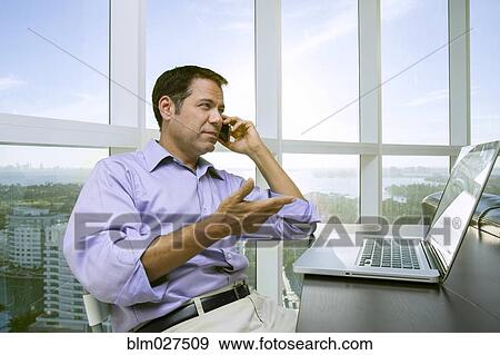 Stock Photo - Hispanic businessman talking on cell phone. Fotosearch