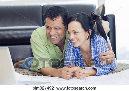 Hispanic couple examining blueprints in living room View Large Photo Image Stock Image - Hispanic couple examining blueprints in living room. Fotosearch