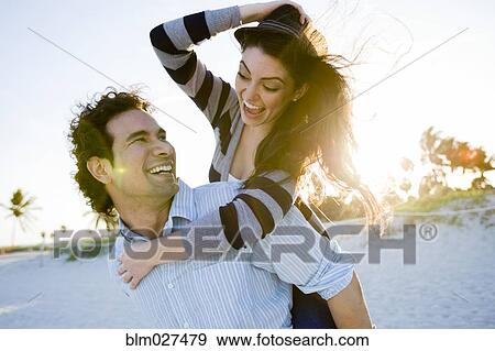 Stock Photo - Hispanic couple playing on beach. Fotosearch