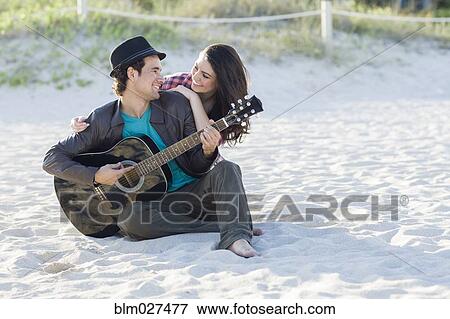 Stock Photo - Hispanic couple relaxing on beach. Fotosearch
