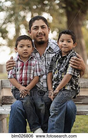 Hispanic father and sons sitting on park bench View Large Photo Image Stock Photograph - Hispanic father and sons sitting on park bench. Fotosearch