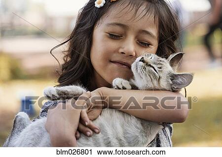 Stock Image - Hispanic girl cradling cat. Fotosearch