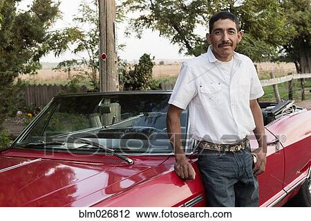 Stock Image - Hispanic man leaning on convertible. Fotosearch