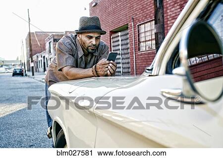 Hispanic man using cell phone on vintage car View Large Photo Image Stock Image - Hispanic man using cell phone on vintage car. Fotosearch
