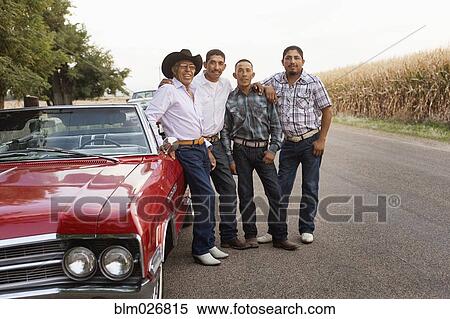 Stock Photography - Hispanic men smiling by convertible. Fotosearch