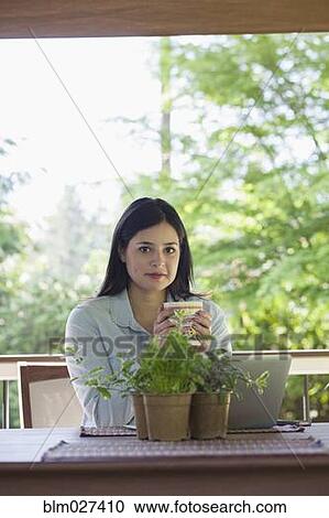 Stock Image - Hispanic woman having cup of coffee. Fotosearch