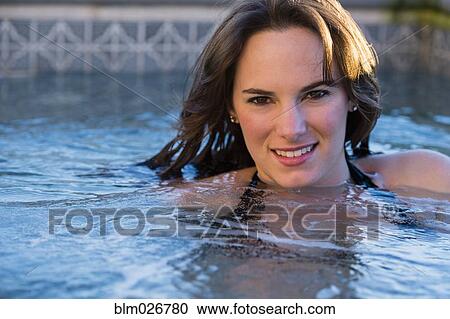 Stock Image - Hispanic woman swimming in pool. Fotosearch