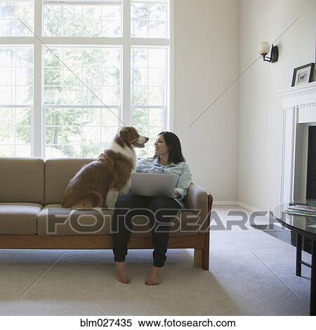 Stock Photography - Hispanic woman using laptop with dog. Fotosearch