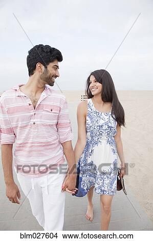 Picture - Indian couple holding hands on beach. Fotosearch