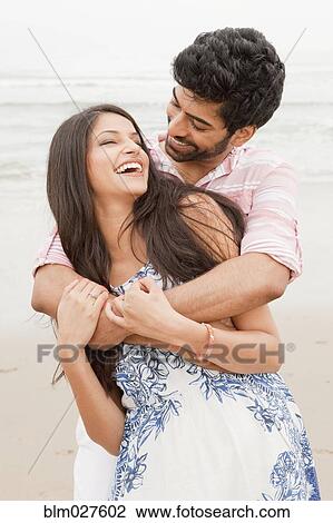 Stock Image - Indian couple hugging on beach. Fotosearch