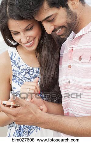 Indian couple using cell phone on beach View Large Photo Image Stock Photo - Indian couple using cell phone on beach. Fotosearch