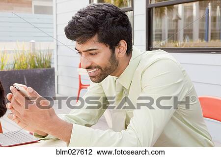 Stock Image - Indian man using cell phone. Fotosearch