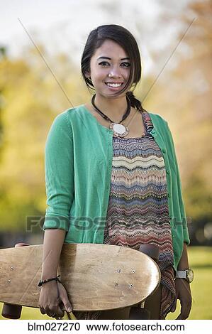 Indonesian woman carrying skateboard View Large Photo Image Stock Image - Indonesian woman carrying skateboard. Fotosearch
