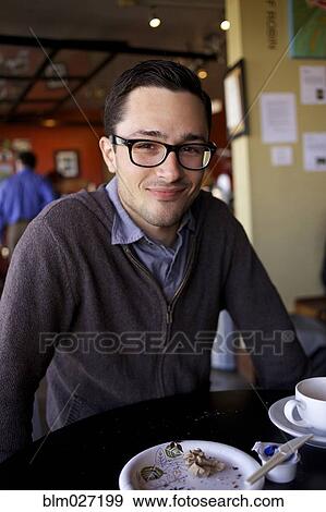 Stock Photo - Man smiling at table in cafe. Fotosearch
