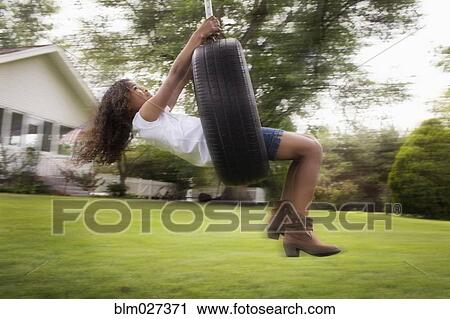 Mixed race girl playing on tire swing View Large Photo Image Stock Image - Mixed race girl playing on tire swing. Fotosearch