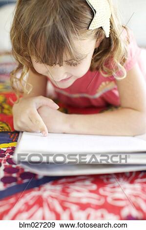 Stock Photo - Mixed race girl reading on bed. Fotosearch
