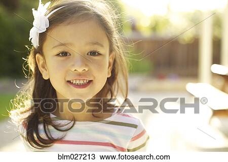 Stock Image - Mixed race girl smiling outdoors. Fotosearch