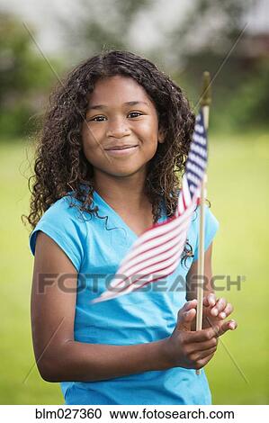 Stock Image - Mixed race girl waving American flag. Fotosearch