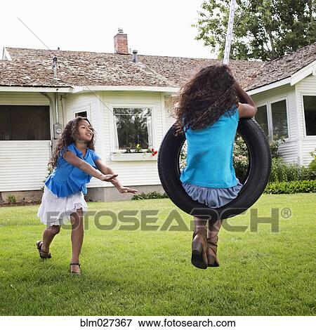 Mixed race girls playing on tire swing View Large Photo Image Stock Photo - Mixed race girls playing on tire swing. Fotosearch