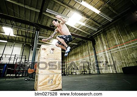 Stock Photo - Mixed race man exercising in gym. Fotosearch