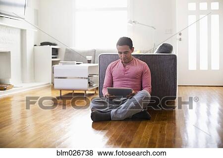 Mixed race man using digital tablet in living room View Large Photo Image Stock Photo - Mixed race man using digital tablet in living room. Fotosearch