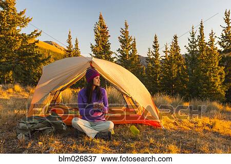 Stock Photo - Mixed race woman camping in rural landscape. Fotosearch