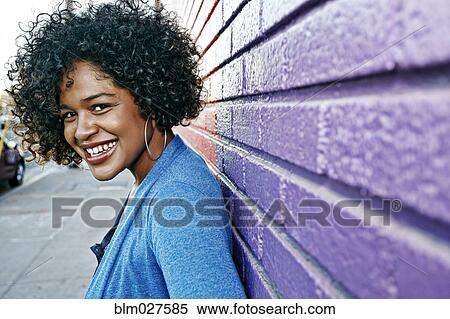 Mixed race woman standing by colorful wall View Large Photo Image Stock Photography - Mixed race woman standing by colorful wall. Fotosearch