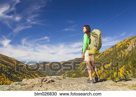 Stock Image - Mixed race woman standing on rocky hilltop. Fotosearch