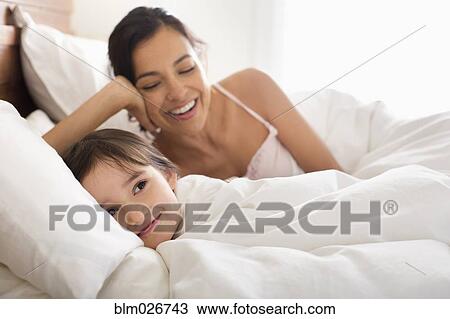 Stock Image - Mother and daughter laying in bed. Fotosearch