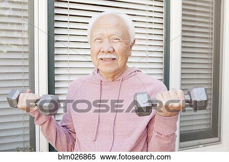 Stock Photography - Older Asian man lifting weights outdoors. Fotosearch