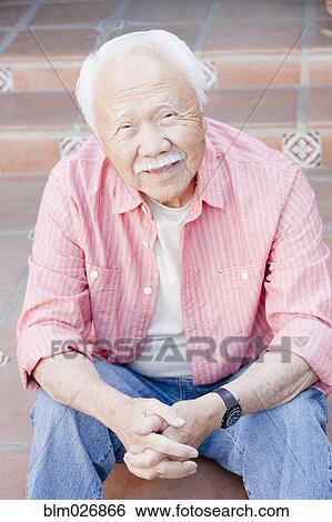 Stock Photograph - Older Asian man smiling outdoors. Fotosearch