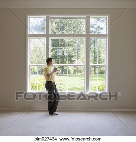 Pacific Islander man standing at window in empty room View Large Photo Image Picture - Pacific Islander man standing at window in empty room. Fotosearch