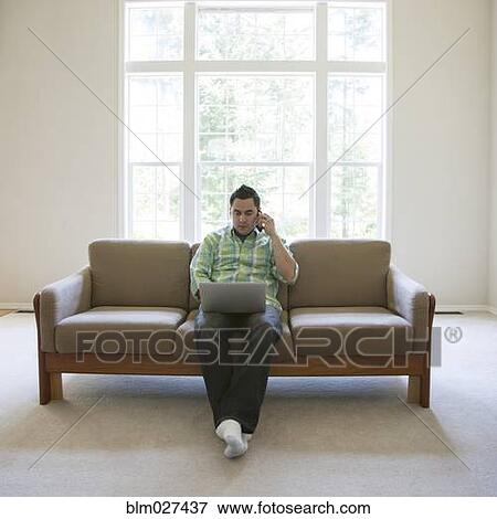 Stock Photo - Pacific Islander man using laptop and cell phone. Fotosearch